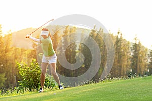 Asian Sporty woman golfer player doing golf swing tee off on the green, people presumably does exercise. Healthy Sport