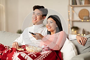 Asian Spouses Enjoying Christmas Eve Watching TV In Living Room