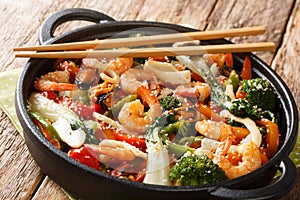 Asian stir fried shrimp, squid and mussels with fresh seasonal vegetables close-up in a pan. horizontal