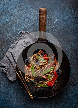 Asian stir fry noodles with vegetables in black wok pan