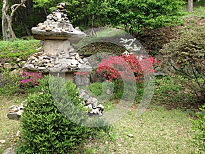 Asian stone structure and next to a bush with red flowers