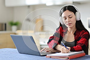 Asian student e-learning and taking notes in the kitchen