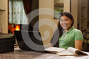 Asian student girl smiling to camera while studying at home