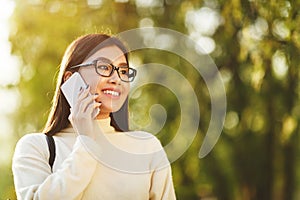 Asian student girl talking on phone in city park