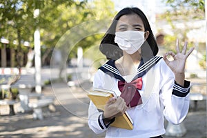 Asian student hold book and wear mask in school uniform