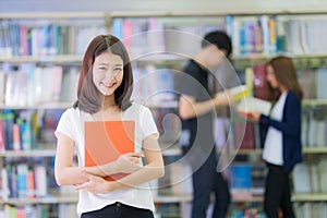 Asian student lady smile and read a book in library