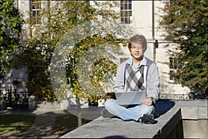 Asian student outdoors with laptop