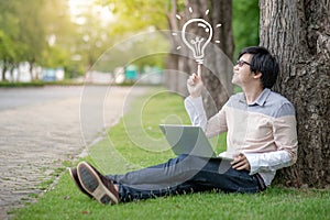 Asian student pointing at light bulb using laptop