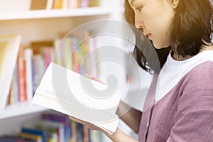 Asian student reading some textbooks in university library