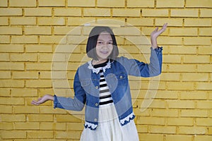 Asian student young girl hold book on her head  with yellow blocks wall in happy emotion