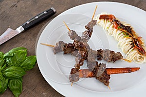 Asian style grilled teriyaki beef skewers on a white plate, top view. Delicious appetizer