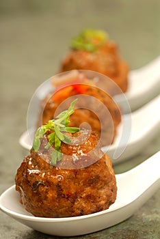 Asian styled meatballs on spoons with a variety of toppings