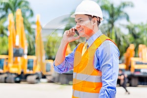 Asian supervisor telephoning on construction site