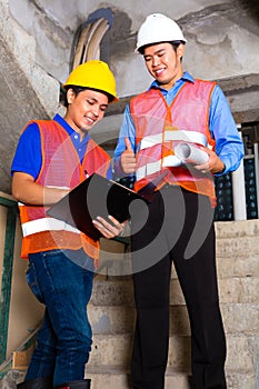 Asian supervisor and worker on building site