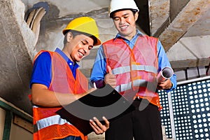 Asian supervisor and worker on building site