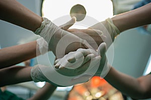 Asian surgeon and nurse with medical mask standing and join hand in operation theater at a hospital. Team of Professional surgeons