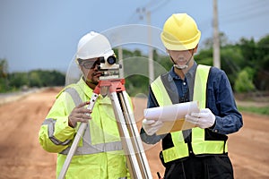 Asian surveyor engineer two people checking level of soil with Surveyor\'s Telescope equipment to measure leveling