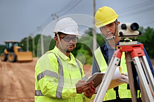 Asian surveyor engineer two people checking level of soil with Surveyor\'s Telescope equipment to measure leveling