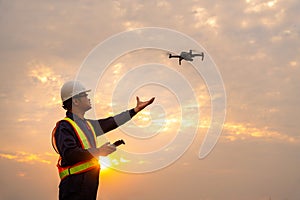 Asian surveyors or explorer deploying drones to view construction sites or check security at sunset