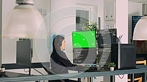 Asian system engineer programming app code on monitors with greenscreen