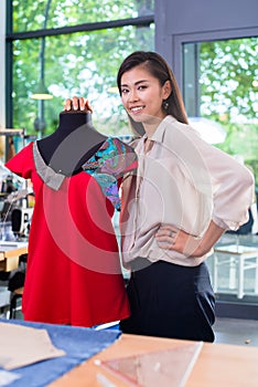 Asian tailor adjusts garment design on mannequin