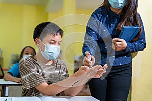 Asian teacher and children with face mask at school after covid-19 quarantine and lockdown and using antiseptic for coronavirus