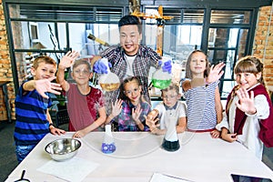 Asian teacher doing experiments with dry ice for children at classroom in modern school. During experiment scientist