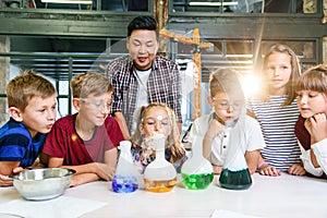 Asian teacher doing experiments with dry ice for children at classroom in modern school. During experiment scientist