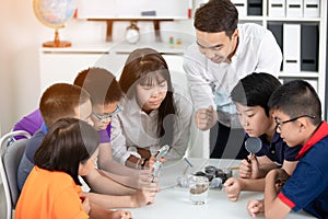 Asian teacher expanding to student in geology class with different of rock .