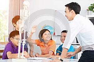 Asian teacher explains a human body structure to little pupil