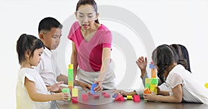 Asian teacher lets Asian students playing colorful wooden blocks toy together, concept for classroom.