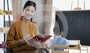 Asian teacher At preschool Helping Children in Class in class room