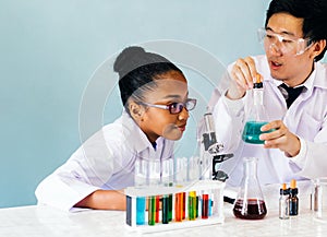 Asian teacher teaching science class to African American student