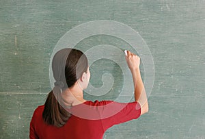 Asian teacher writing on blackboard with chalk in classroom, Educations concept