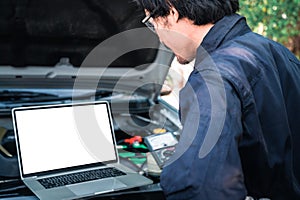 The asian technician analyze the car`s engine graph on laptop computer in the garage. the concept of automotive, repairing,