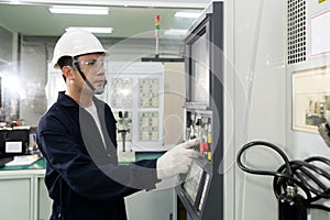Asian technician engineer operating CNC machine in workshop