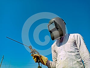 An asian technician holded welding machine handle on sky background with covering mask on sky background with glass mask