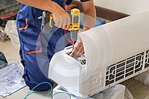 Asian technician man installing an air conditioning in a client house, Young repairman fixing air conditioner unit, Maintenance