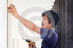 Asian technician man installing air conditioning in a client house, Young repairman fixing air conditioner unit, Maintenance and