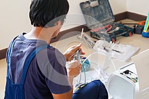 Asian technician man installing air conditioning in client house, Young repairman fixing air conditioner unit, Maintenance and