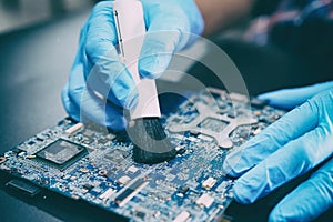 Asian Technician repair and cleaning dirty dust micro circuit main board computer electronic technology with brush
