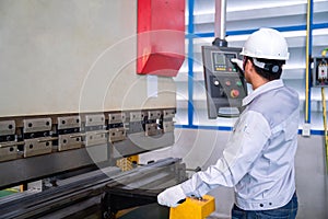 Asian technician worker wearing a safety suit Setting Hydraulic Press Break Machine and Prepared Sheet Metal Shearing in