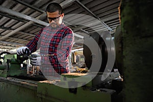 Asian technician working with drilling holes in wood machine in factory. Concept of skill in working job with machine