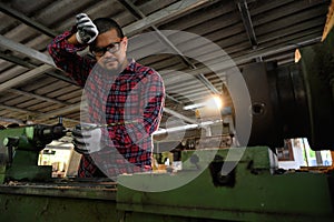 Asian technician working with drilling holes in wood machine in factory. Concept of skill in working job with machine