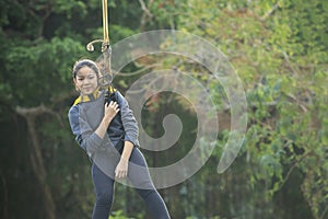 Asian teen age hanging on safety rope in outdoor adventure acti