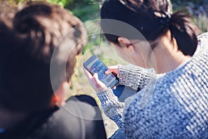 Asian teen boy and girl look in smartphone, communicate, have fun, millenial, teenagers rest together photo