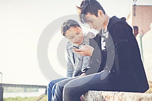 Asian teen boy and girl look in smartphone, communicate, have fun, millenial, teenagers rest together