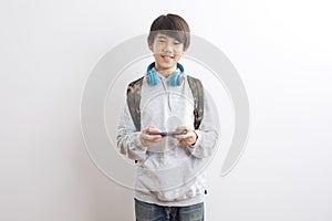 Asian teen boy schooler texting or playing game online on smartphone