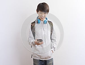 Asian teen boy schooler texting or playing game online on smartphone