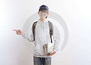 Asian teen boy students carrying a backpack and books pointing finger standing